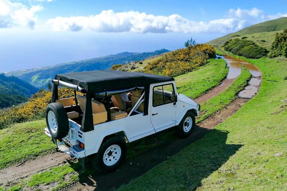một chiếc xe jeep màu trắng đang chạy trên một con đường đất