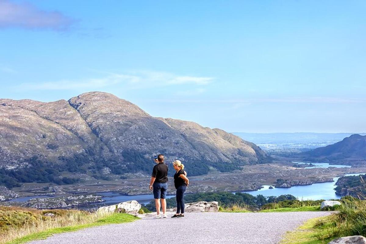 a man and woman standing on a road looking at a mountain