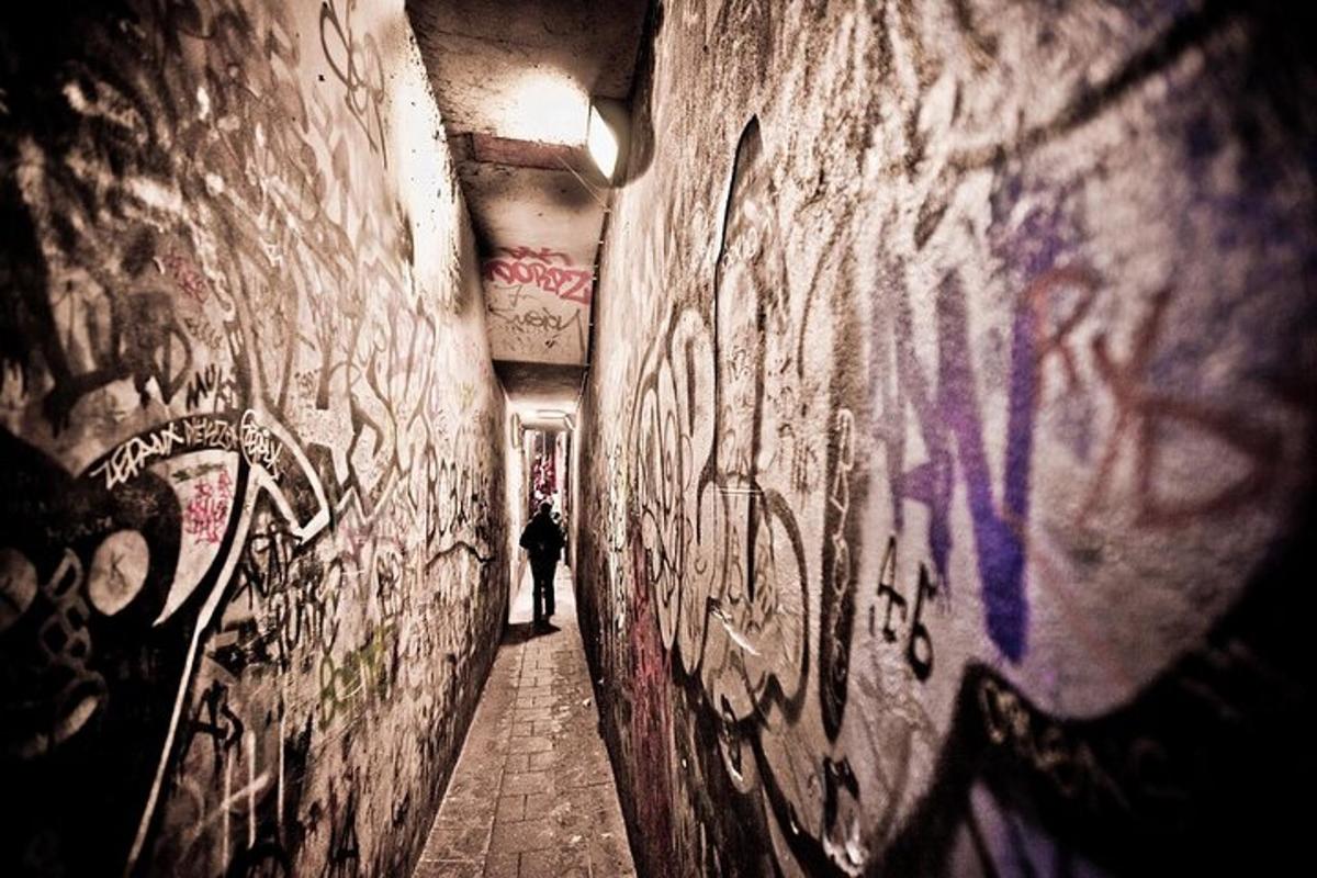 una persona che cammina lungo un vicolo con graffiti sul muro