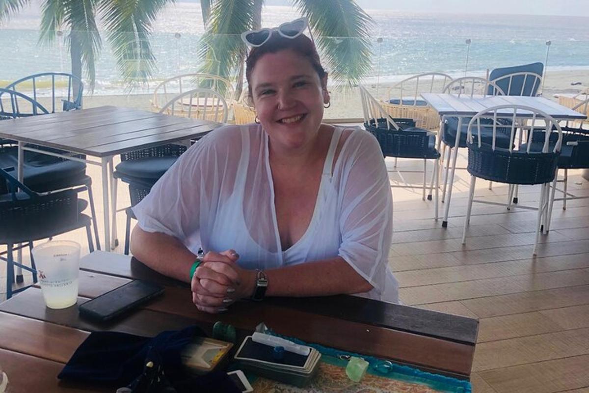 a woman sitting at a table in front of the beach