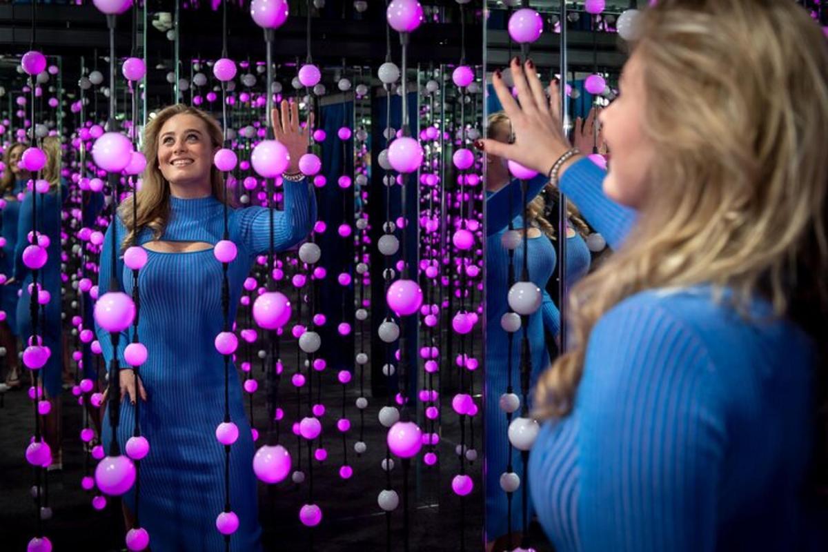 to kvinner som står foran en vegg av rosa baller