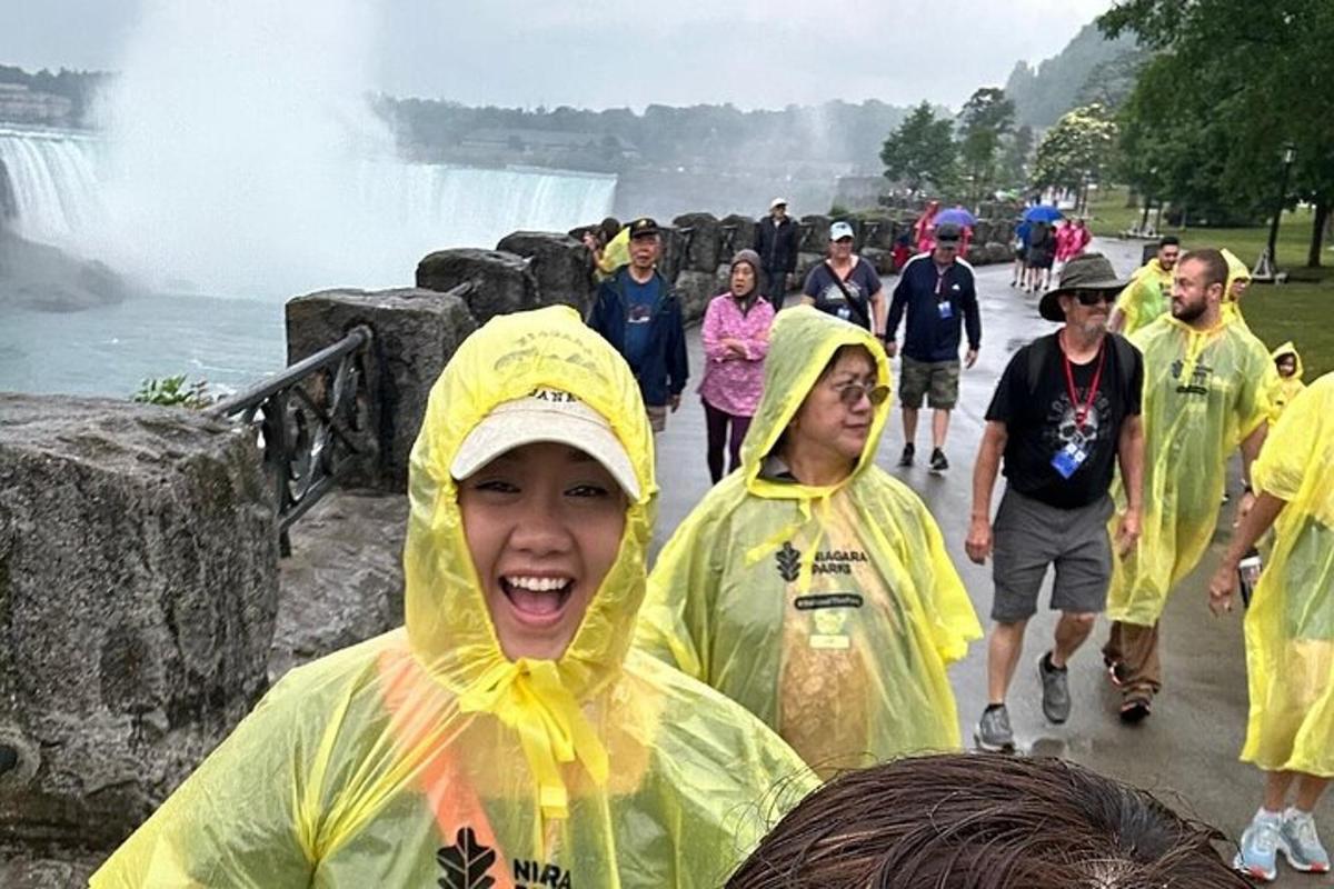 a group of people in raincoats standing in front of a waterfall