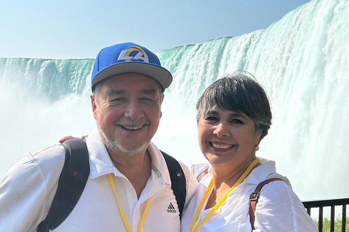 a man and a woman standing in front of a waterfall