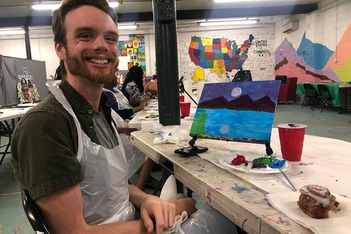 a man sitting at a table with a painting