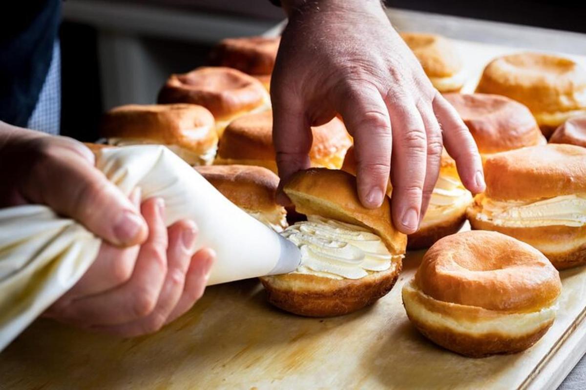 una persona sta mettendo del formaggio su un mucchio di ciambelle
