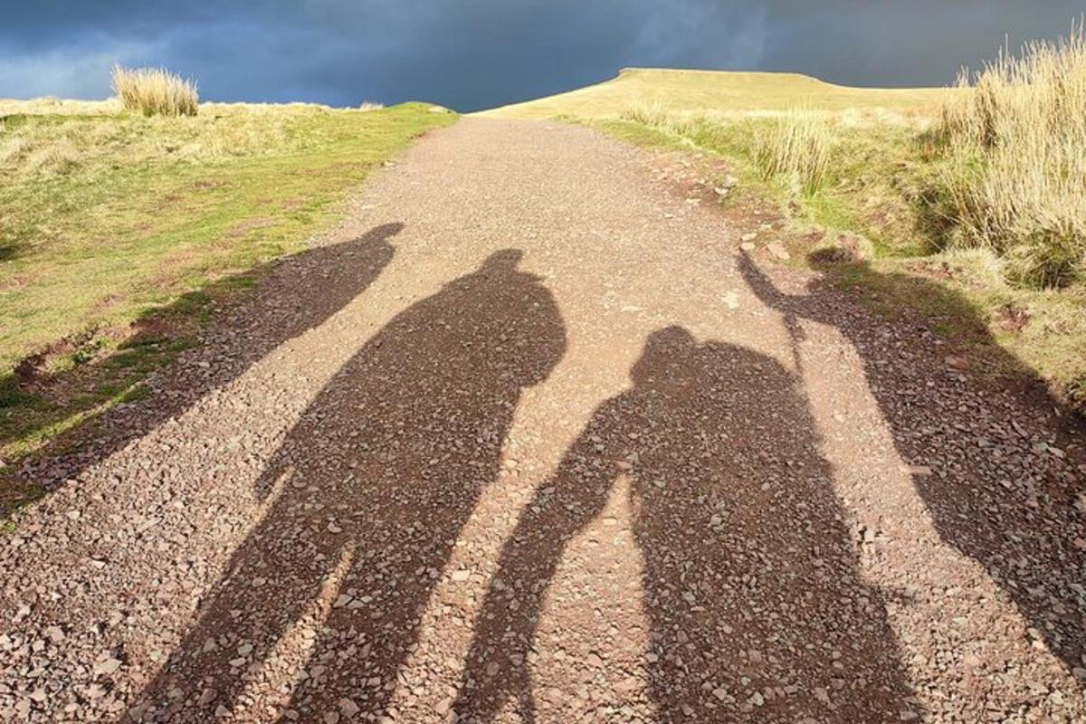 tre skygger av folk som går nedover en grusvei