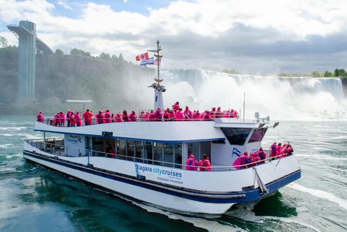 a group of people on a boat in front of a waterfall