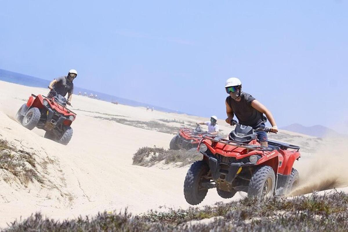két ember ATV-zik a sivatagi homokon