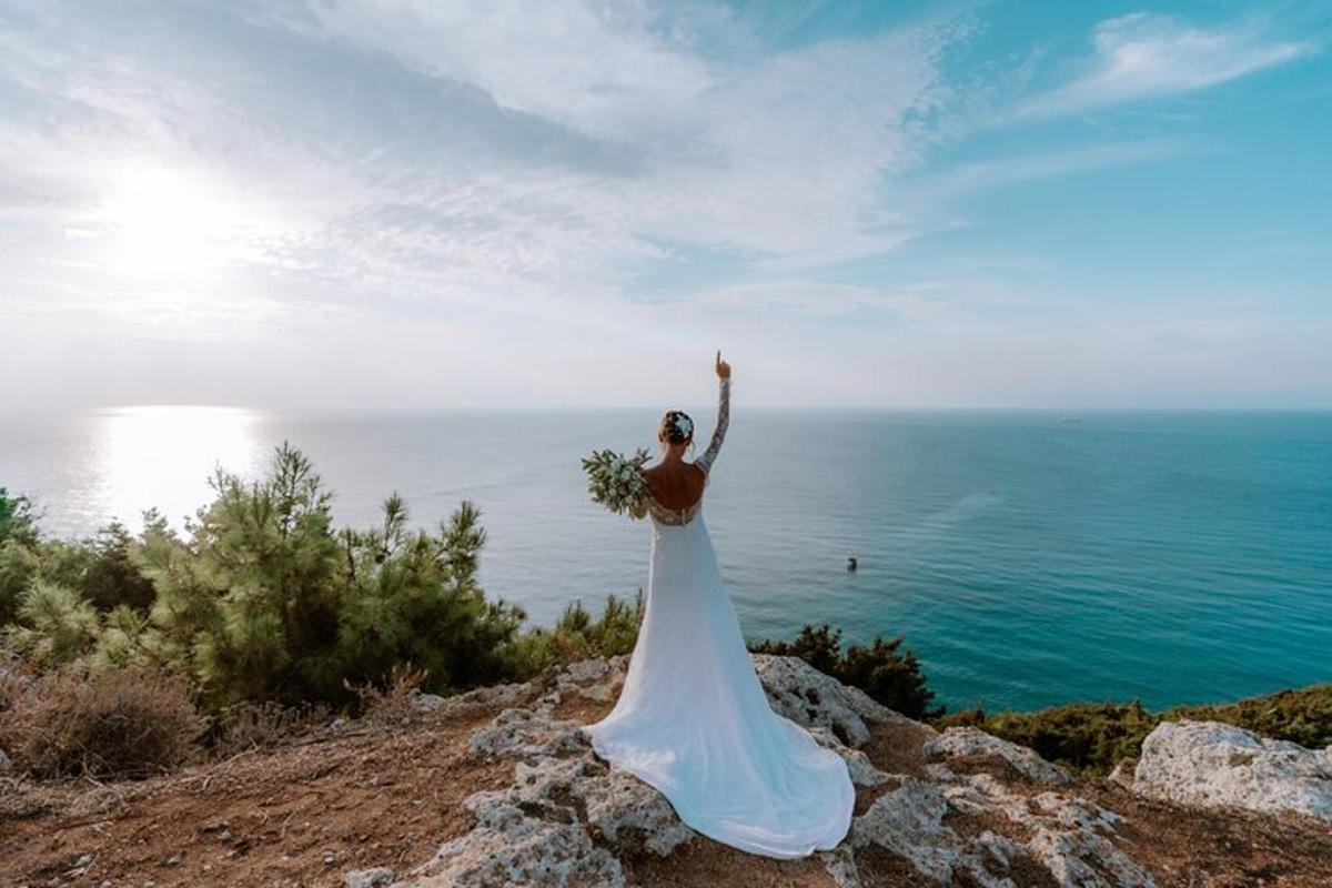 una donna in abito da sposa in piedi in cima a una scogliera