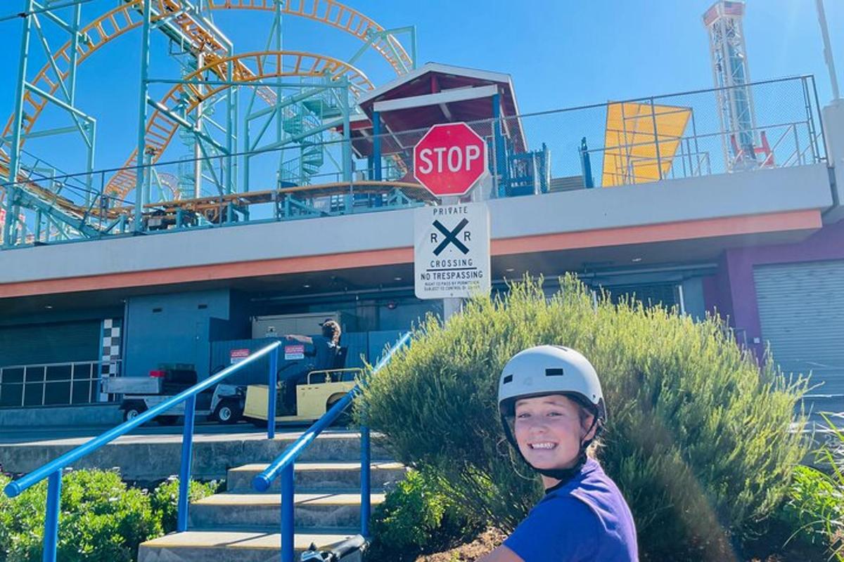 a man wearing a helmet standing in front of a roller coaster