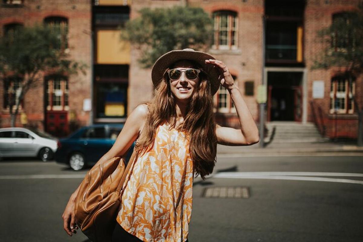 een vrouw met een zonnebril en een hoed die over straat loopt