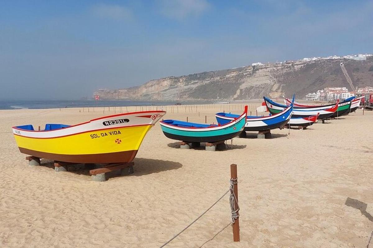a row of boats sitting on a sandy beach