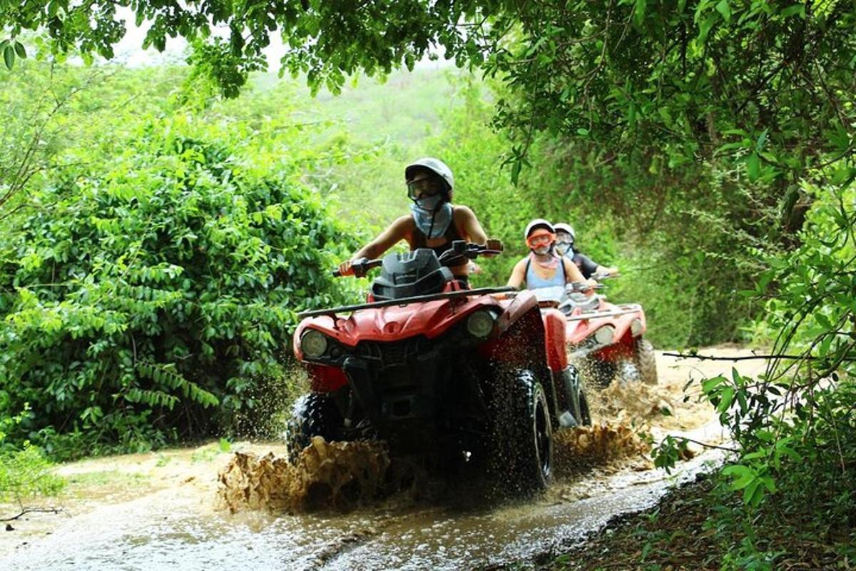 duas pessoas andando em um quadriciclo na lama