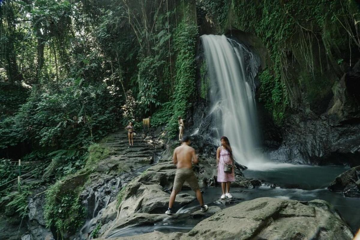 orang berdiri di atas batu di hadapan air terjun