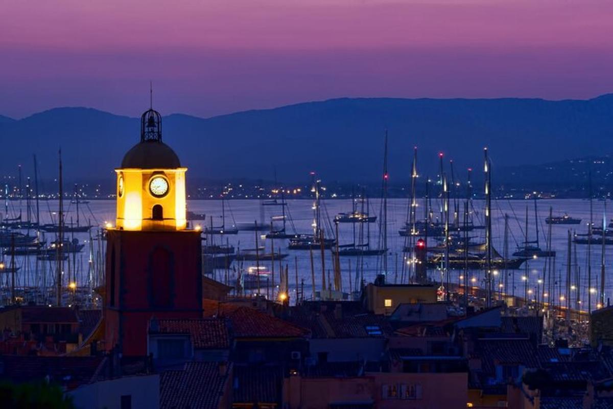 una torre dell'orologio in una città con un porto di notte