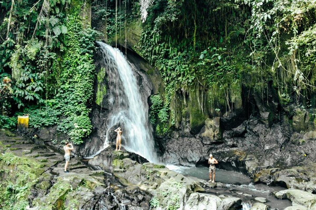 tiga orang berdiri di hadapan air terjun