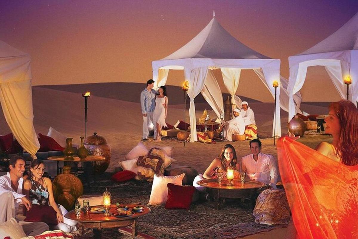 um grupo de pessoas sentadas em frente a tendas no deserto