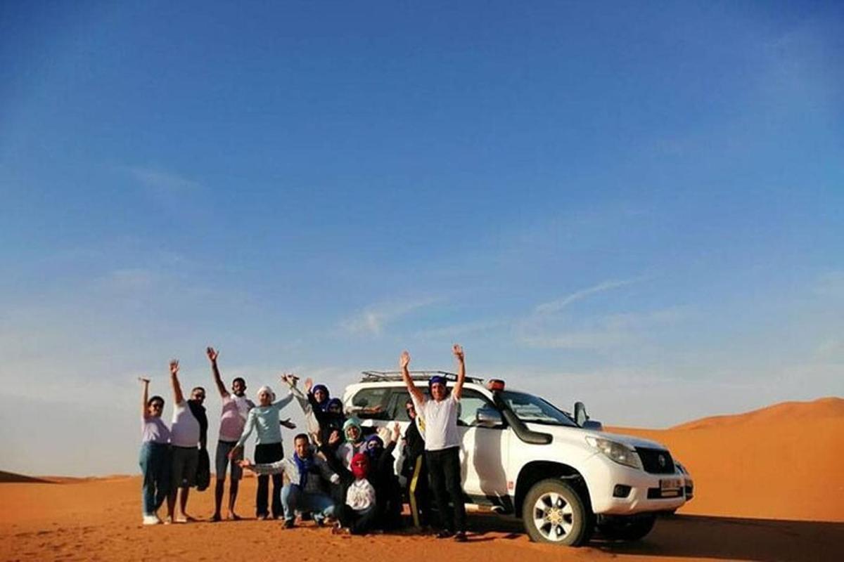 um grupo de pessoas em pé na frente de um carro no deserto