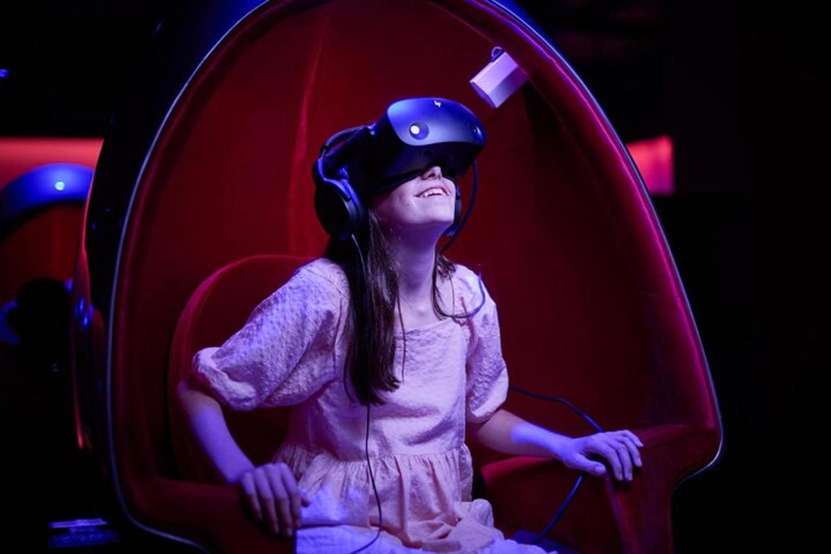 a young girl sitting in a red chair wearing a helmet