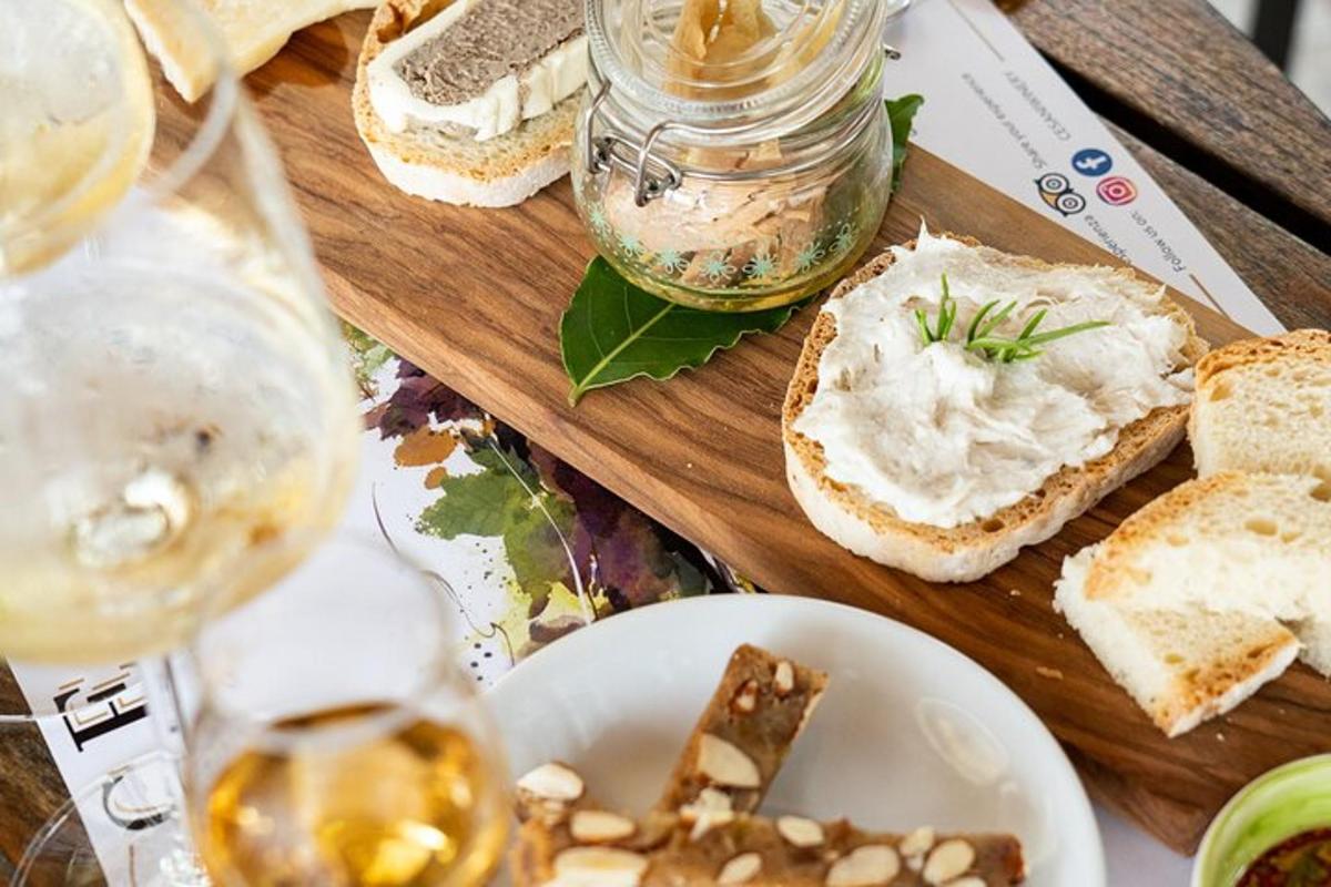 un tavolo con pane, un piatto di cibo e un bicchiere di vino