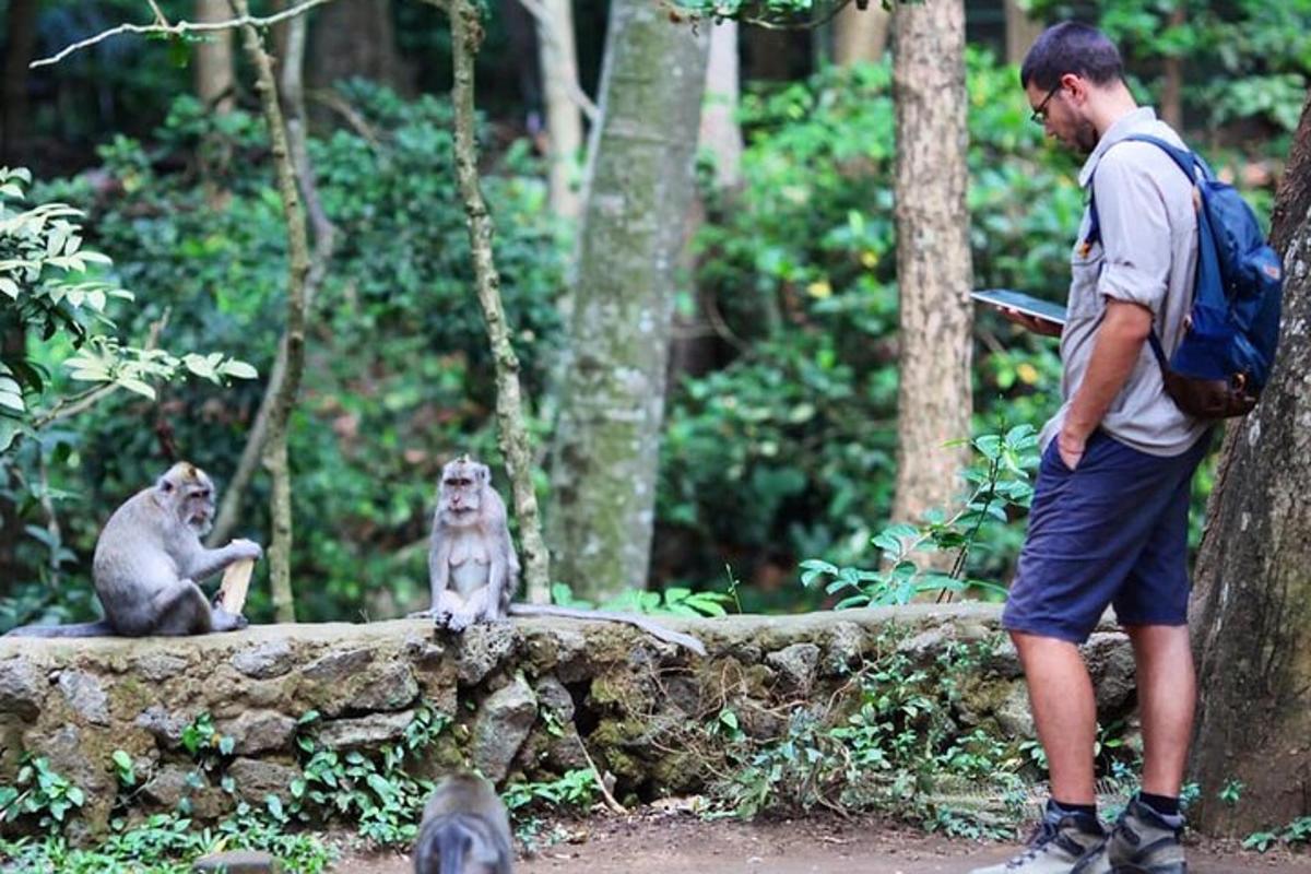 Un hombre de pie junto a dos monos en un bosque.