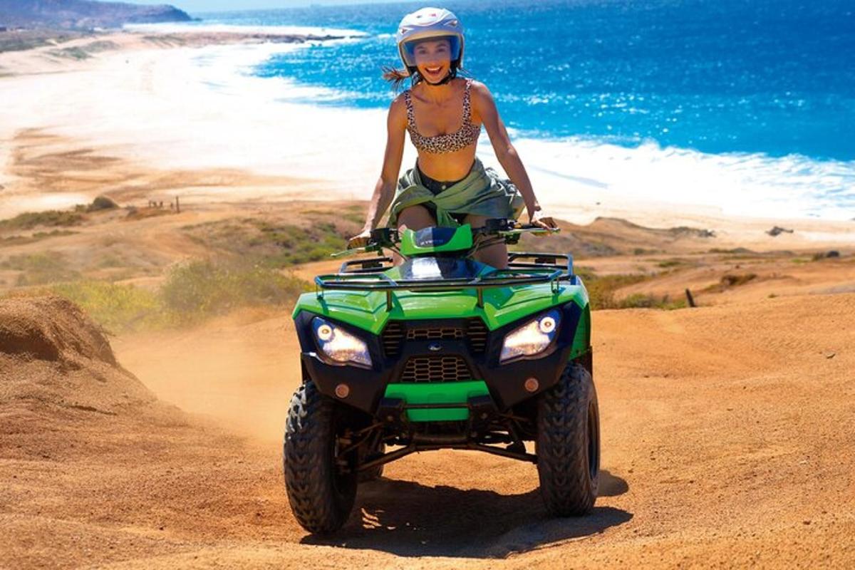 una dona va en un quad per la platja