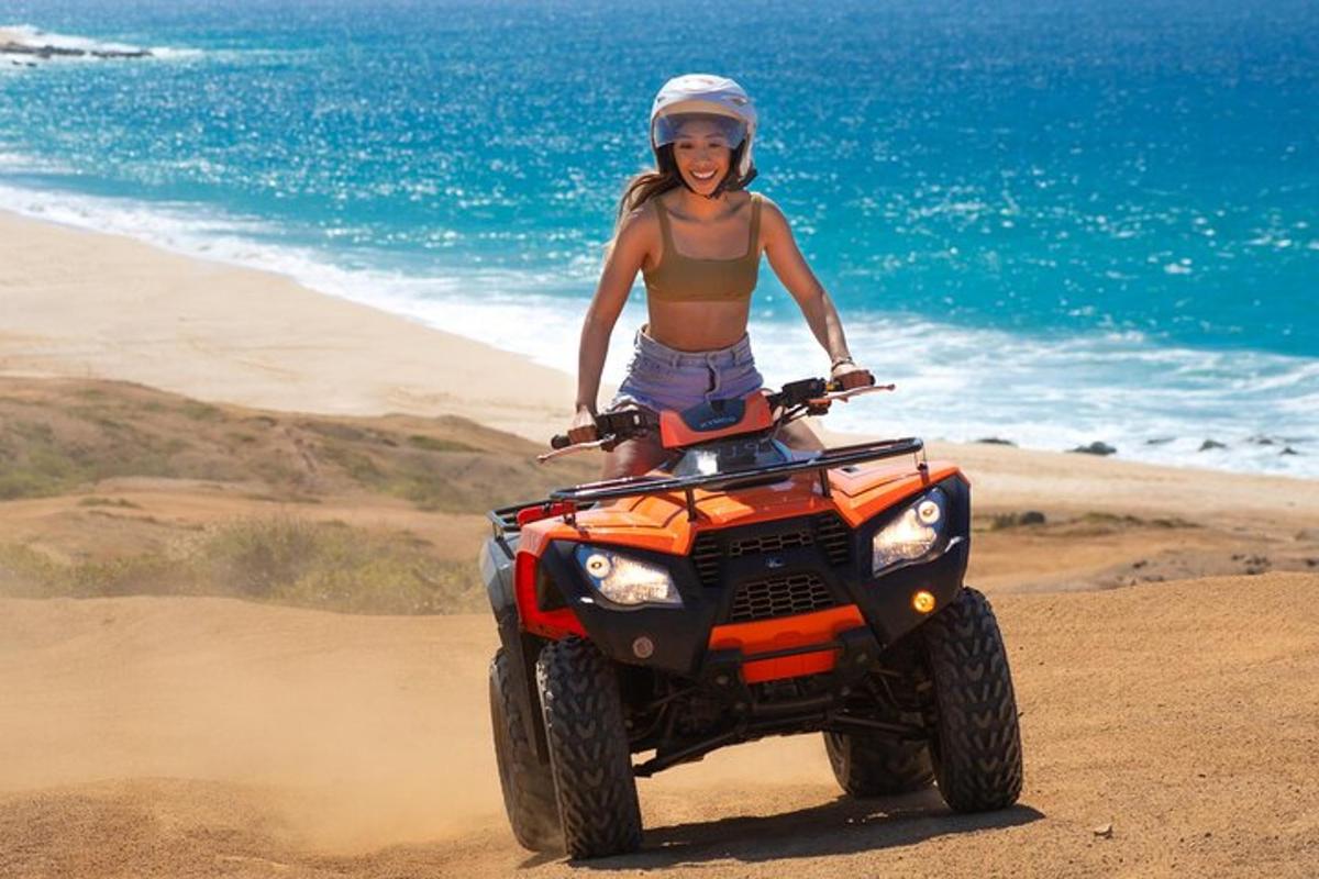 una dona muntant un quad a la platja