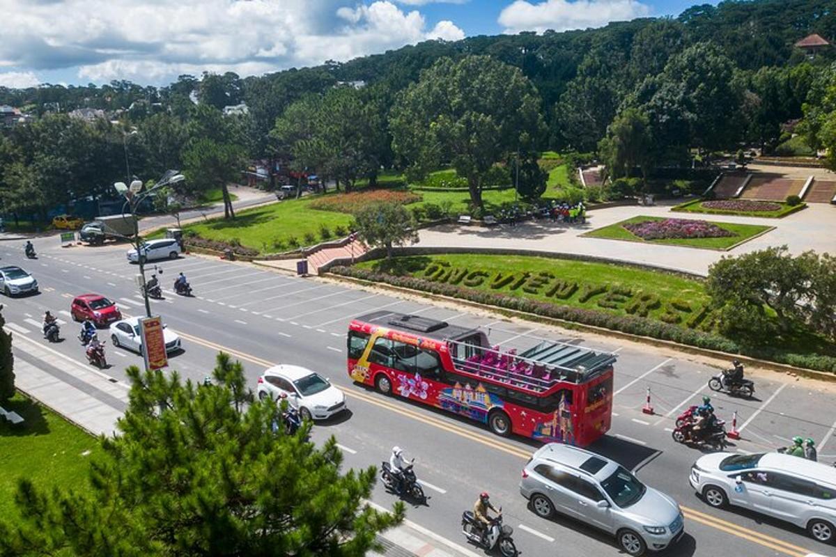 um ônibus vermelho dirigindo por uma rua da cidade com carros