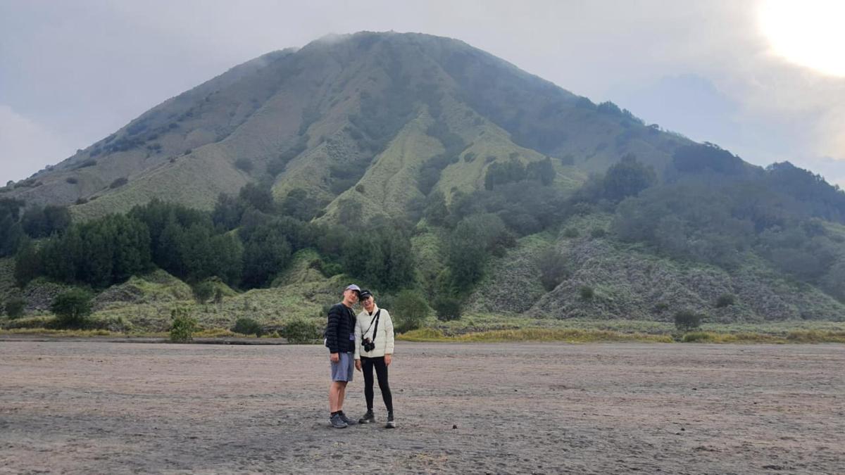 two people standing in a field with a mountain in the background