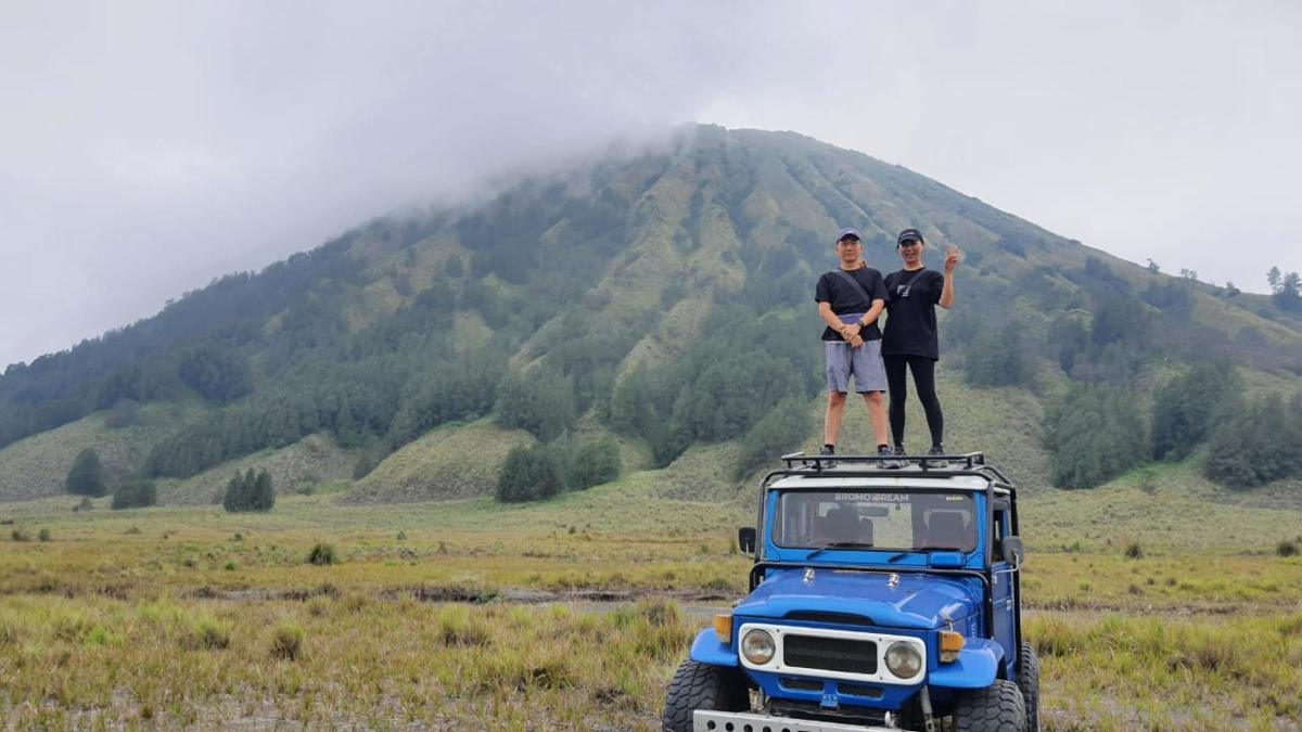 two men standing on top of a blue truck
