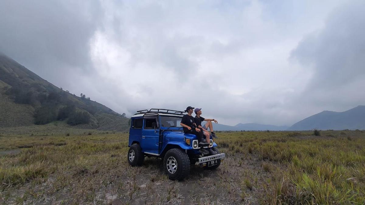 two people sitting on the back of a blue jeep