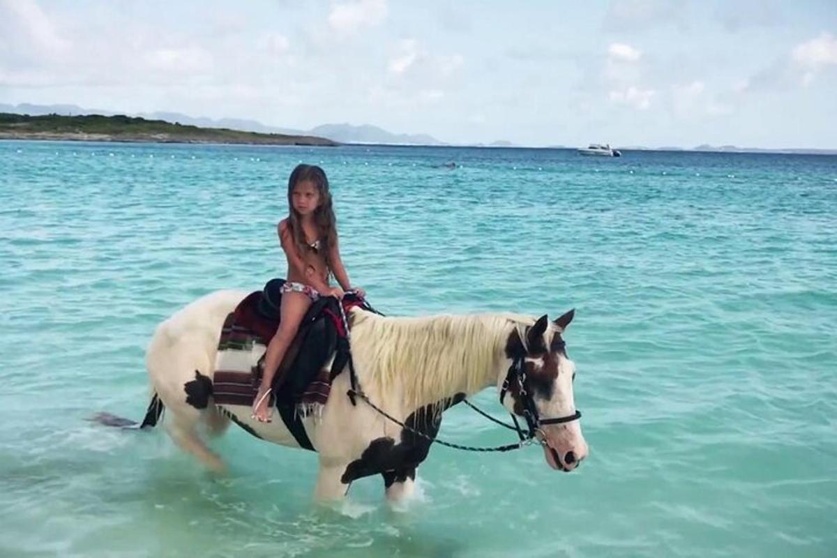 uma jovem cavalgando um cavalo no oceano