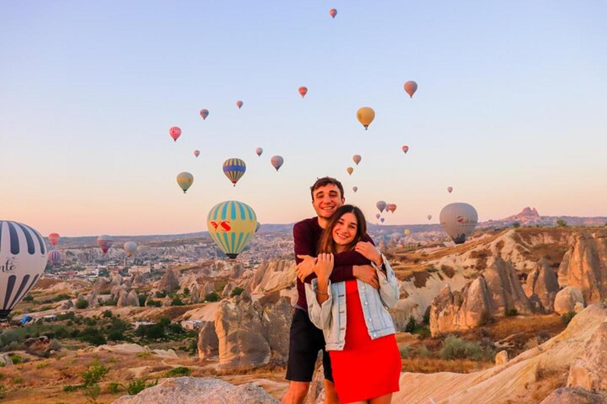 a man and woman standing in front of a view of hot air balloons