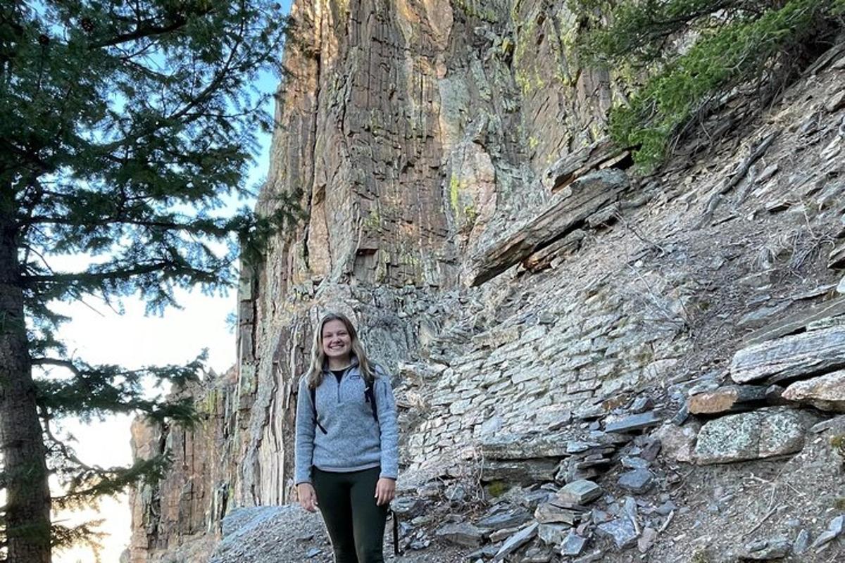 a woman standing in front of a stone wall
