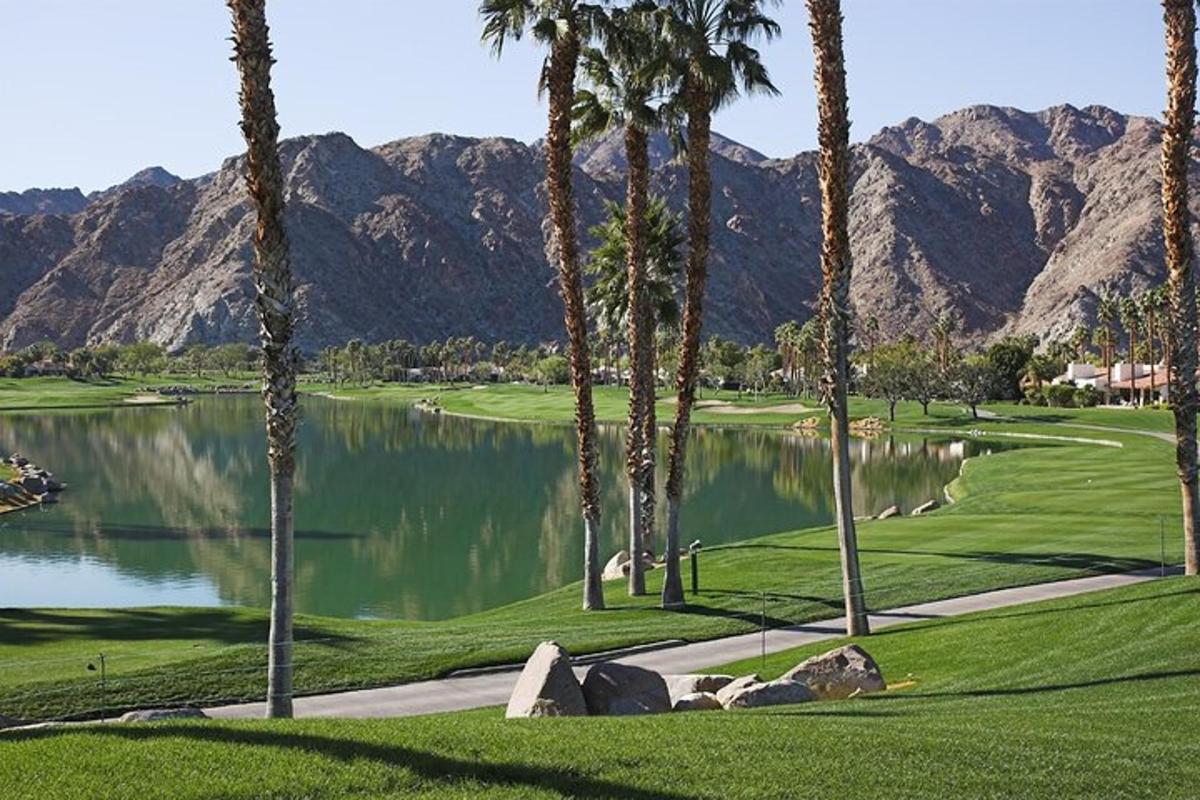 một sân golf có cây cọ và hồ nước