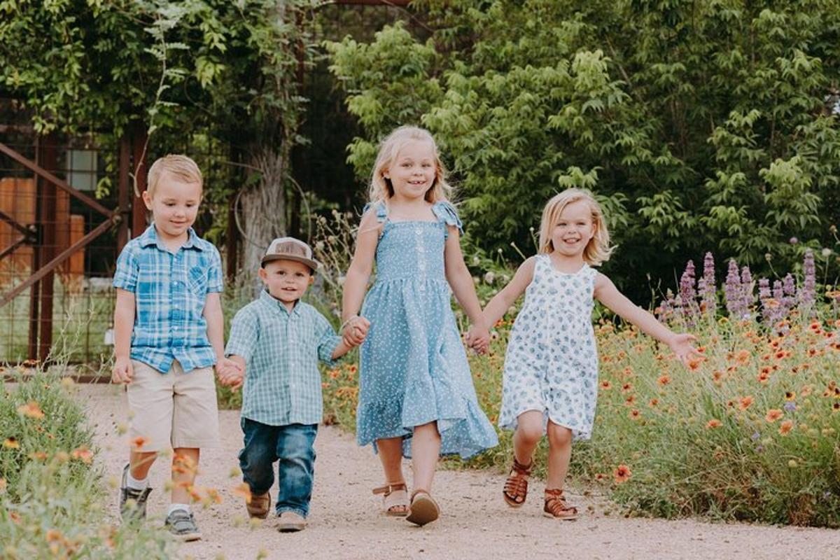 a group of children holding hands while walking down a path