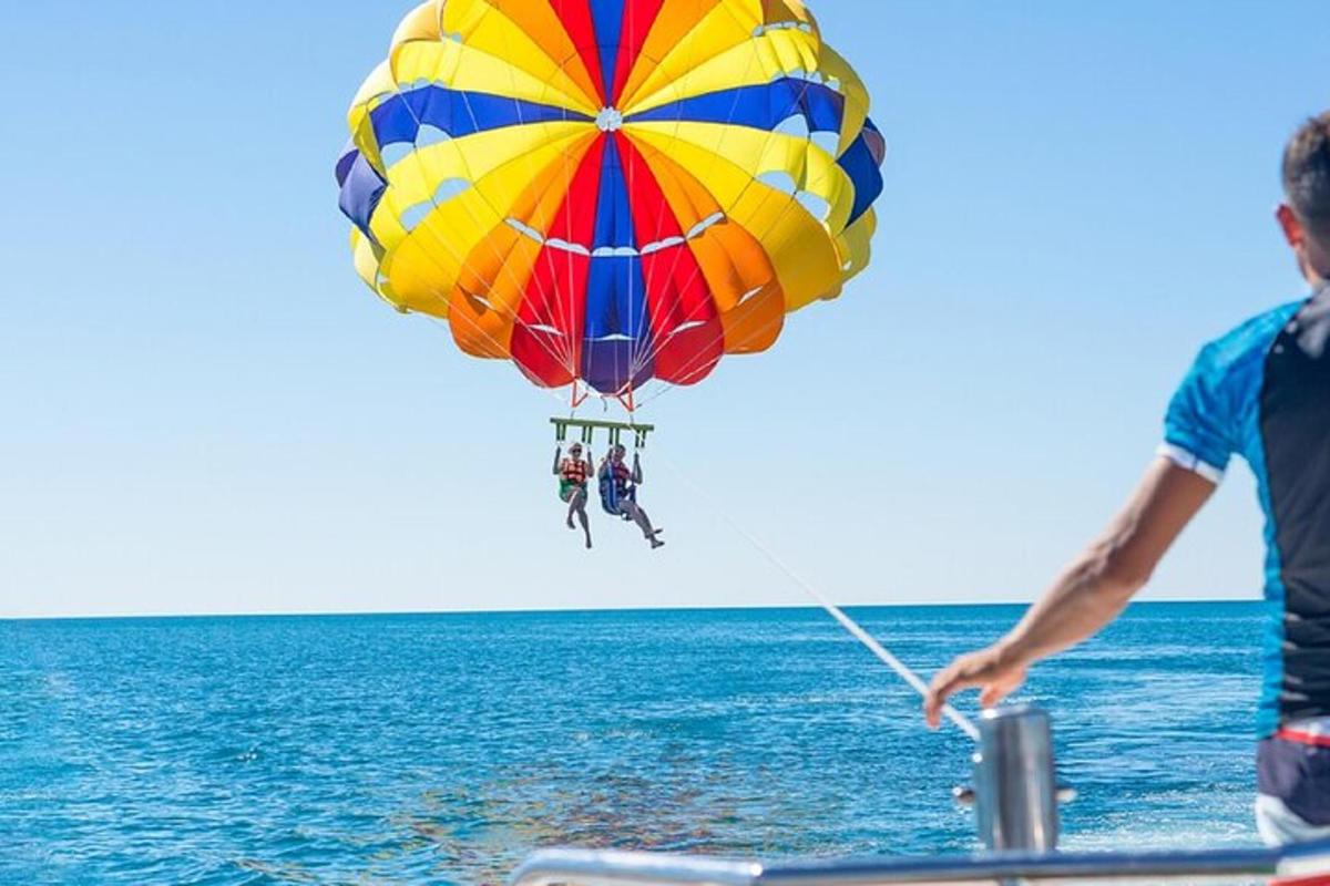 čovjek leti šarenim padobranom iznad oceana
