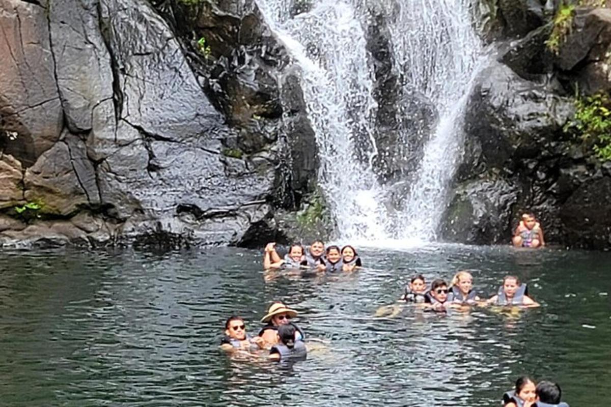 a group of people swimming in the water near a waterfall
