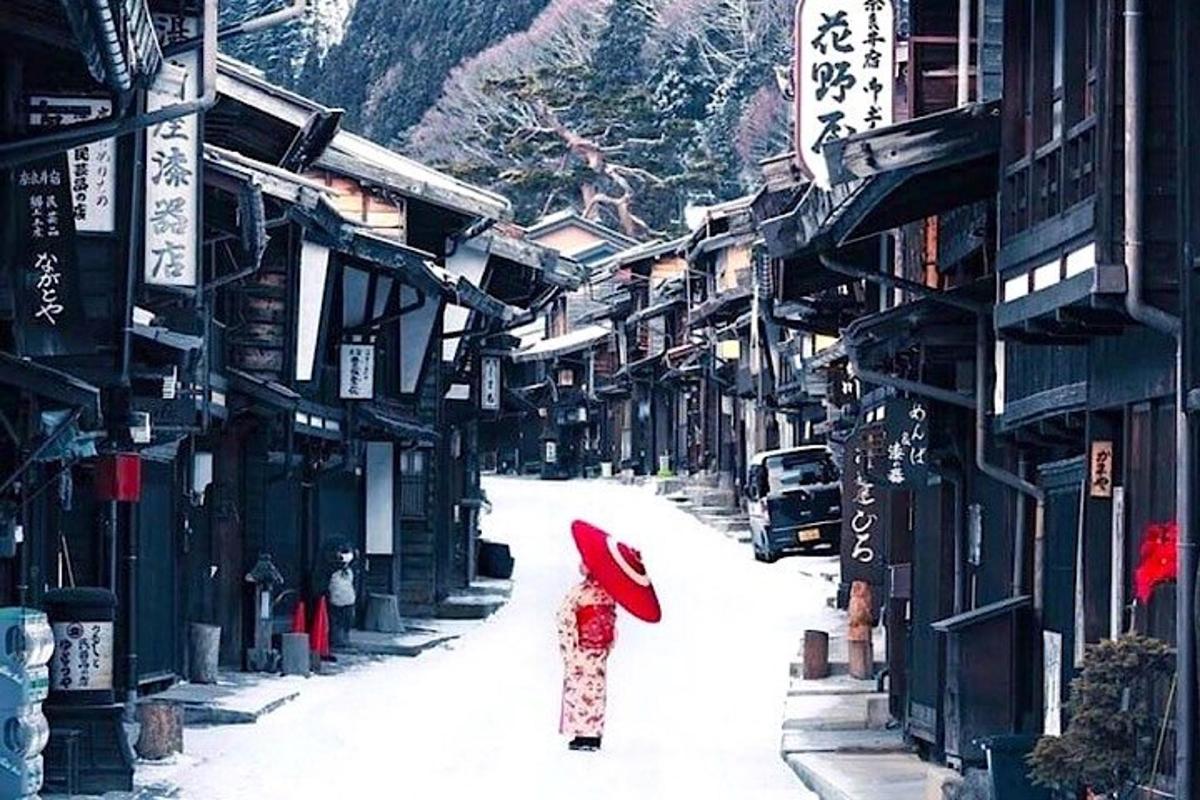 una donna che cammina per strada con un ombrello rosso