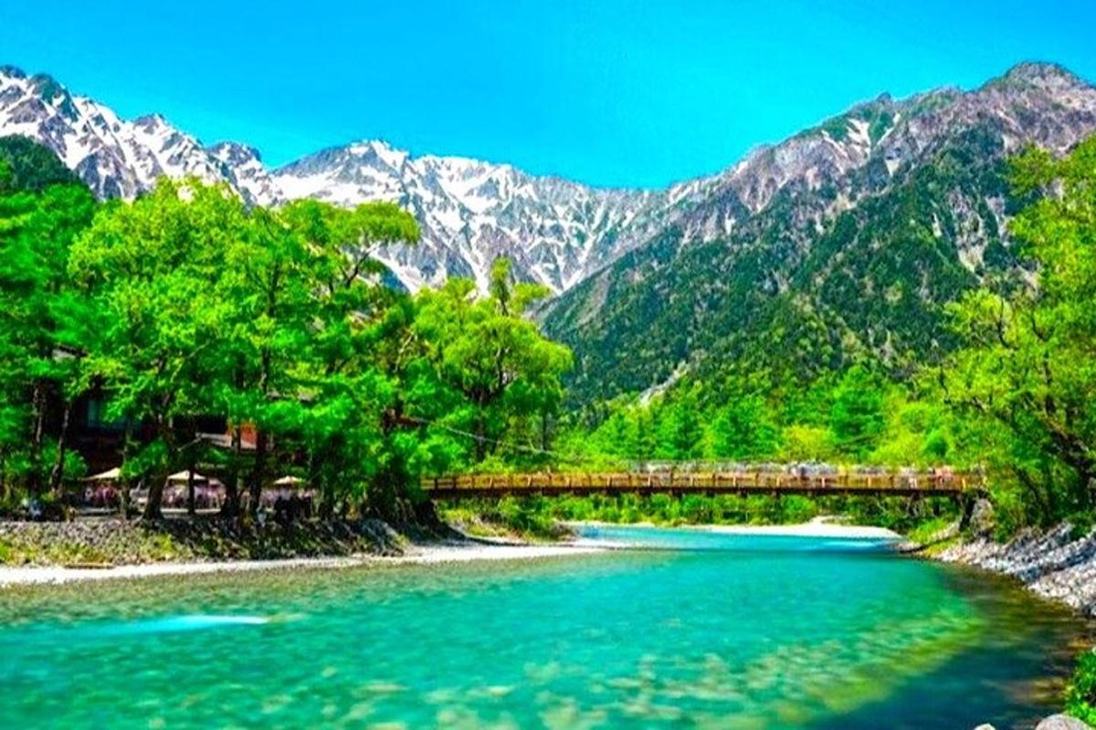 un ponte sopra un fiume con le montagne sullo sfondo