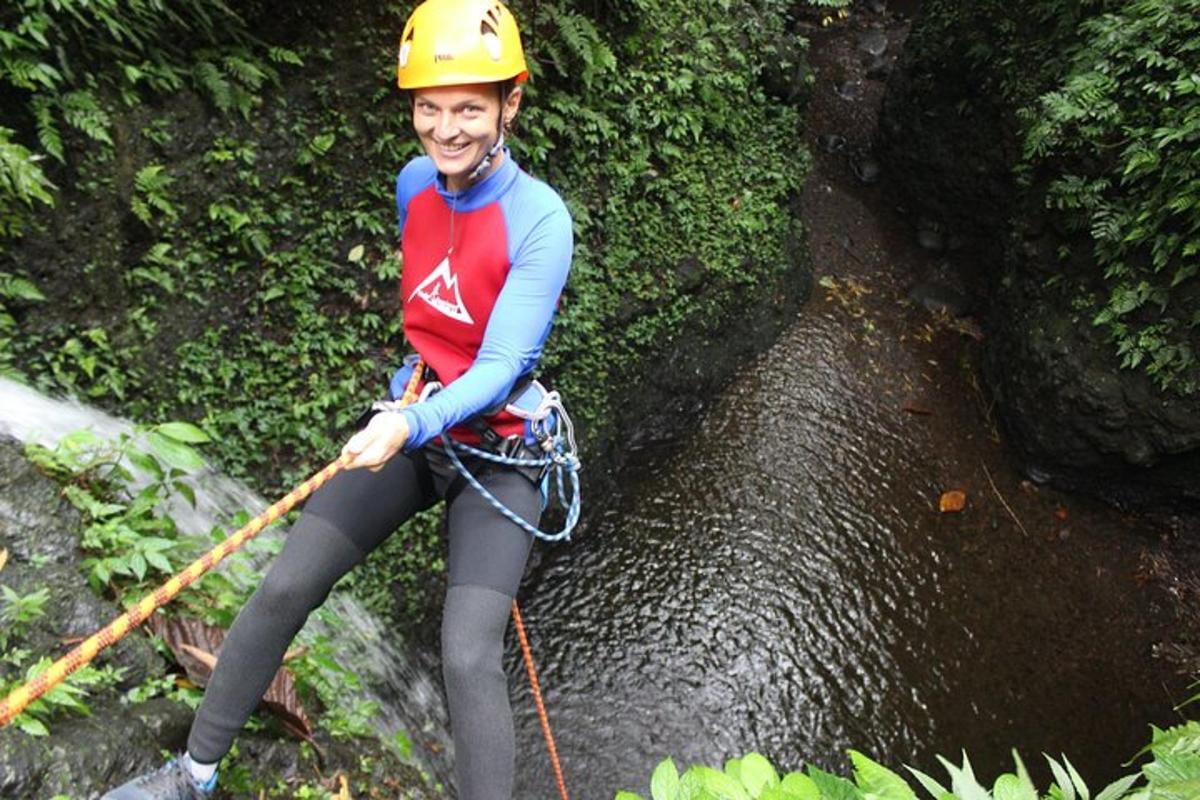 a woman in a helmet on a zip line over a waterfall