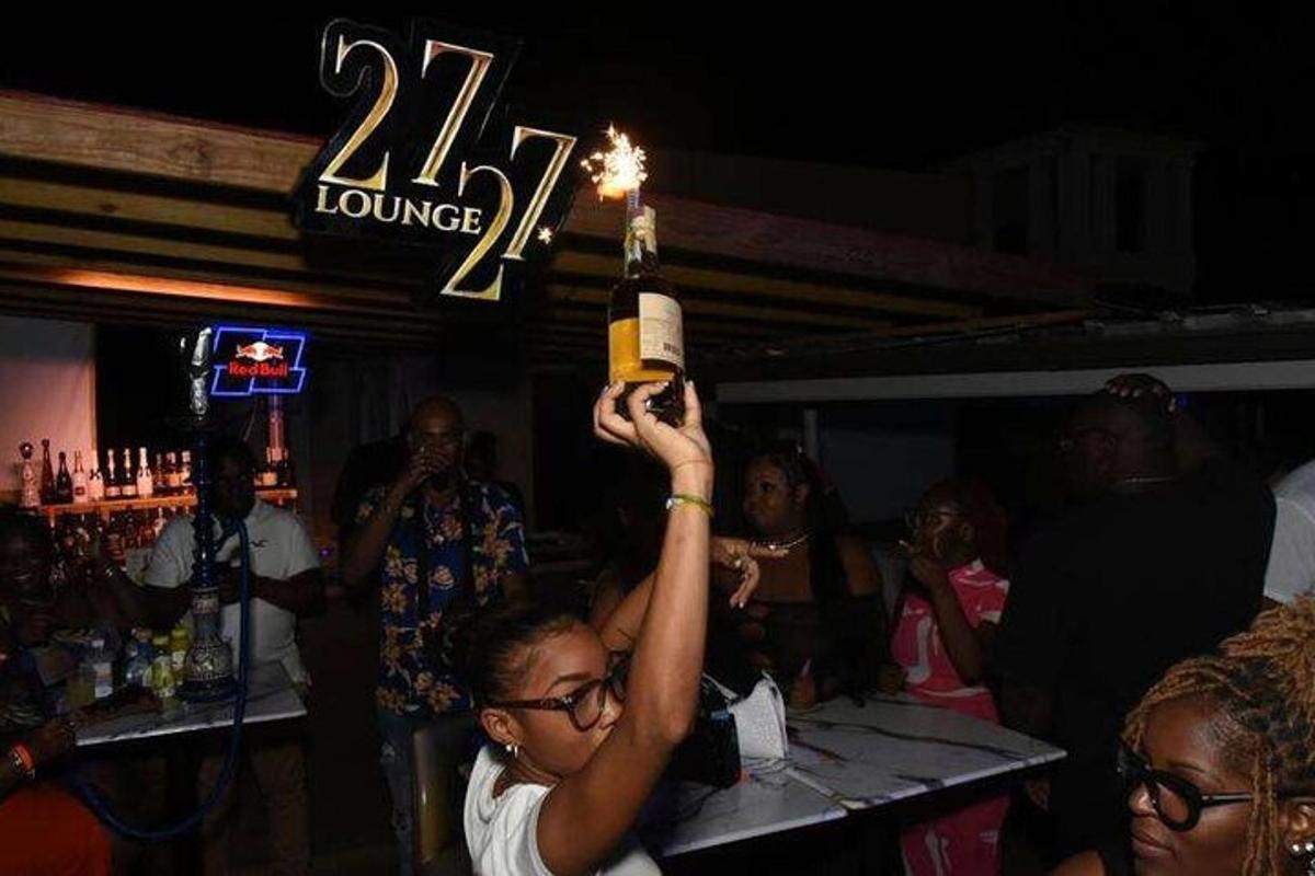 a woman holding up a bottle with a lit candle
