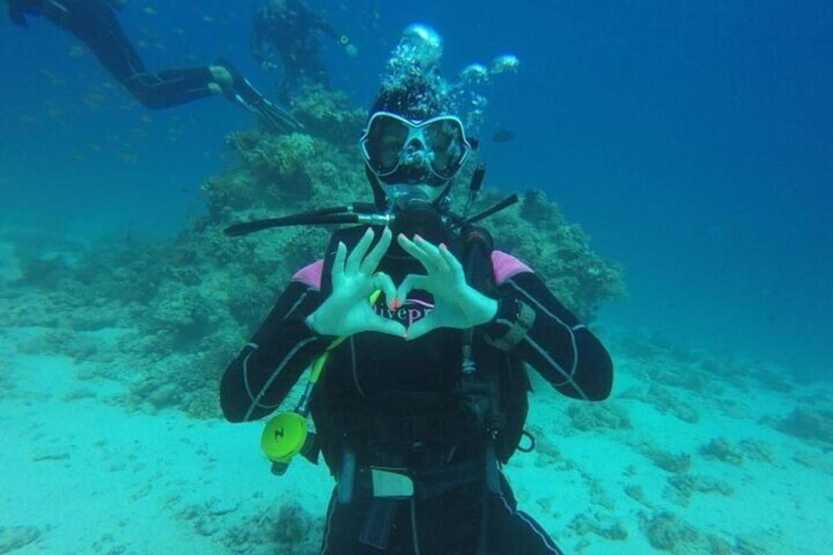una persona in muta da sub che fa il gesto del cuore