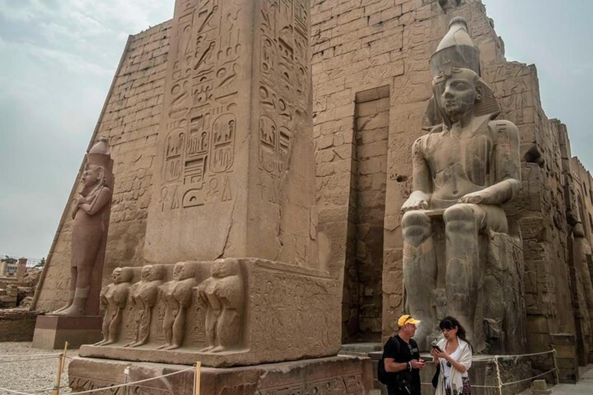 Dos personas de pie frente a una gran estatua