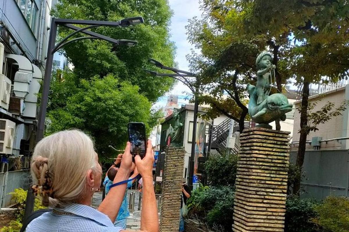 ženska, ki fotografira kip s svojim mobilnim telefonom
