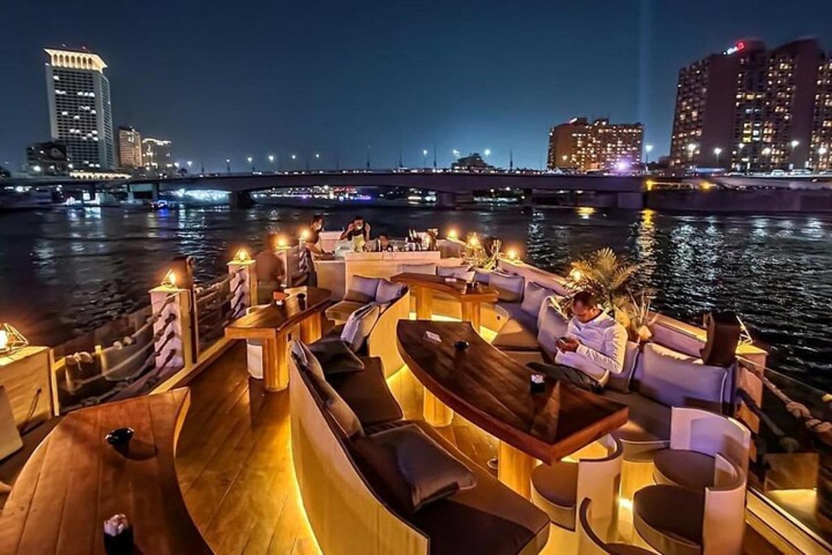a boat with couches and tables on the water at night