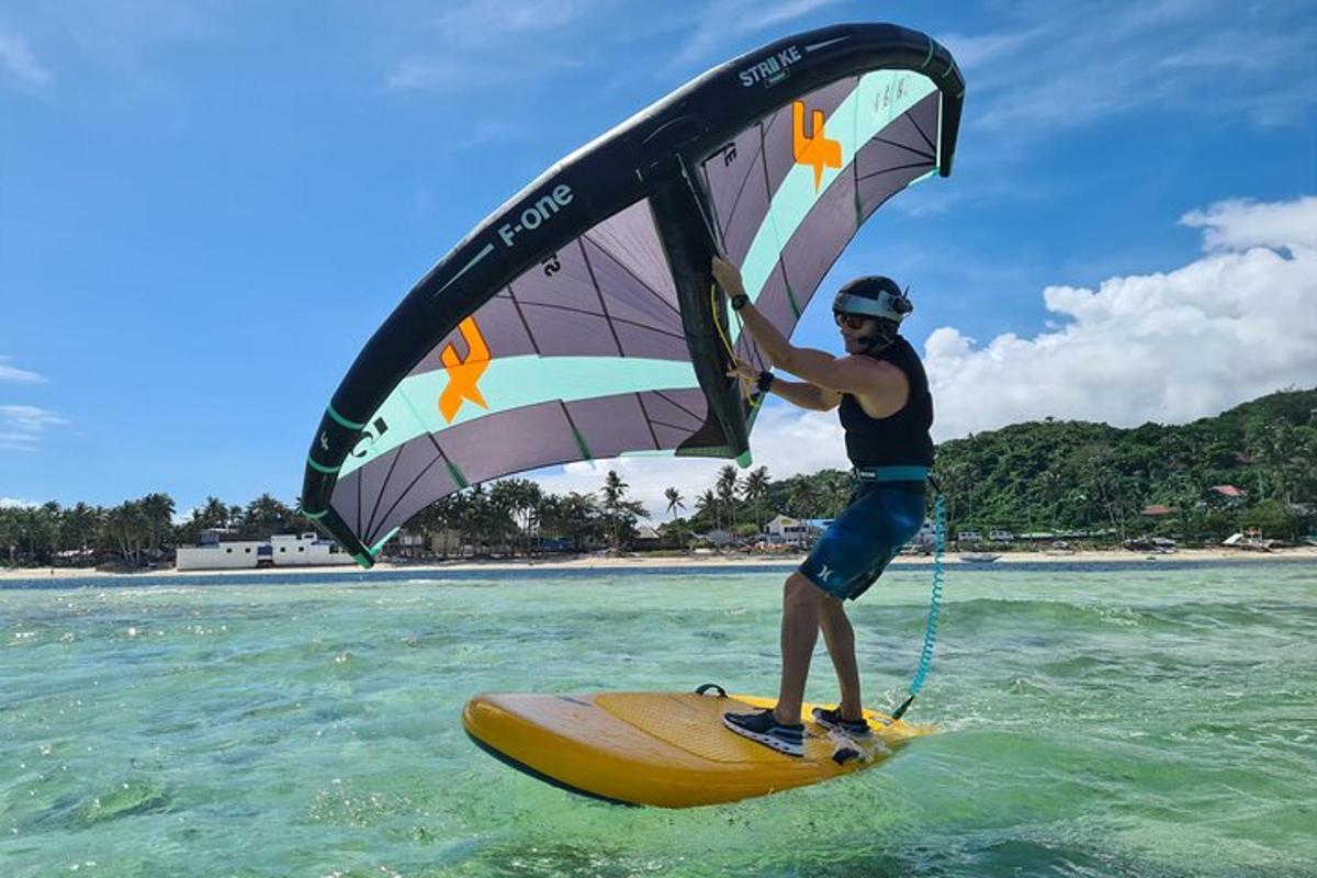 a man holding a sail on a surfboard in the water