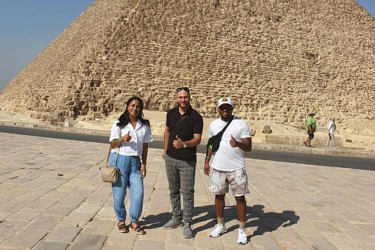 tři lidé stojící před pyramidou