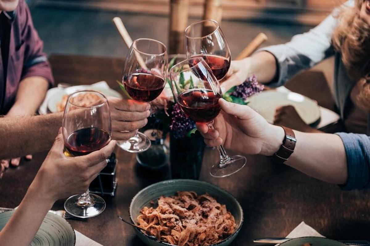un grup de oameni așezați în jurul unei mese, bând vin