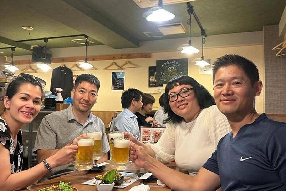skupina lidí sedících u stolu a pijících pivo